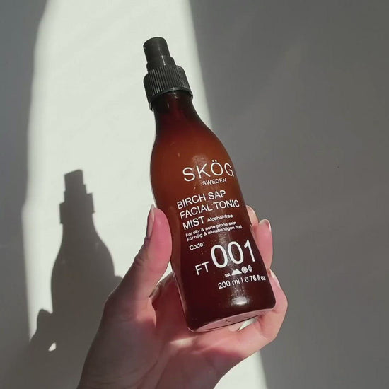 "Video showcasing SKÖG Birch Sap Facial tonic mist  For removing pollutants ,stay hydrating  top black with spray on it dark amber with text on it . Person spraying droplets of Birch Sap facial tonic mist .